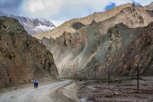 Solo female cyclist on the bicycle on the remote road in Western Tibet