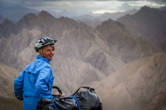 Single female cyclist on the bicycle on the remote road in Western Tibet
