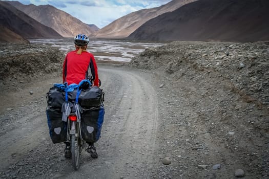 Solo female cyclist cycle touring through the stunning remote landscape of Western Tibet