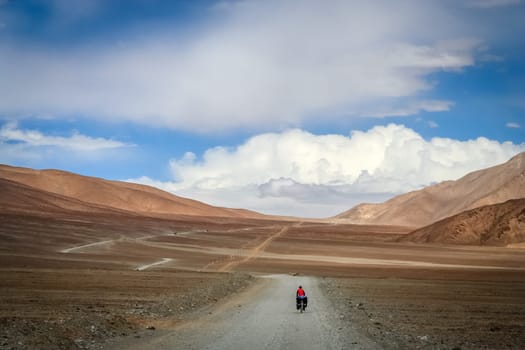 Solo female cyclist cycle touring through the stunning remote landscape of Western Tibet