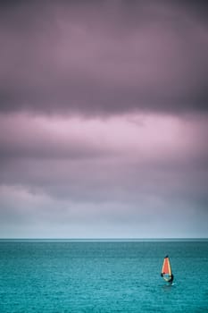 Single man windsurfing on a surface of a sea in Devon, England