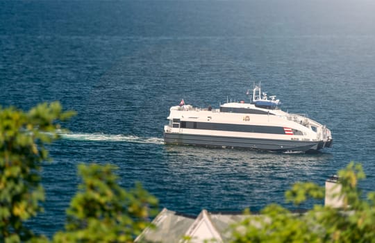 Ship in waters of fiord, Norway, Scandinavia, Europe. Blue and white waves.