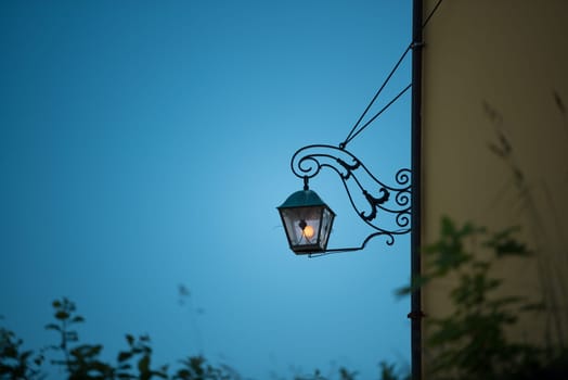 Street light at sunset in Alesund, Norway, Europe. Yellow light of lamp against blue sunset sky.