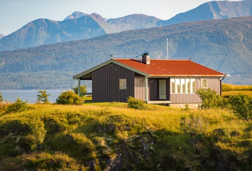 Beautiful landscape of Norway. House on meadow, mountains and sky in background. Travel in Scandinavia, Europe