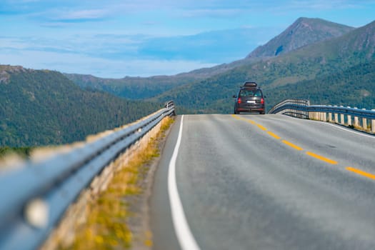 Car on mountain road in Norway, Europe. Auto travel through scandinavia. Blue sky and mountains in background.