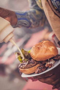 Woman adding mayonnaise to her burger during outside BBQ