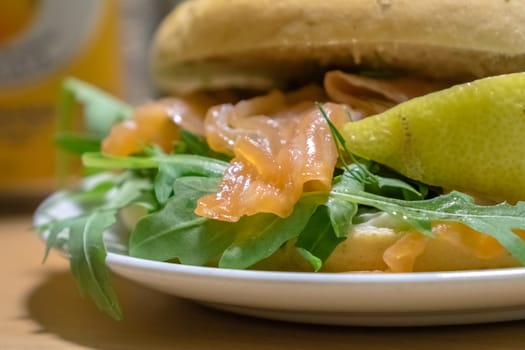 Breakfast bun on a plate, filled with smoked salmon and rocket salad