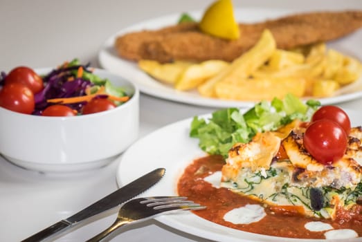 Feta and spinach layered quiche served with tomato sauce, cherry tomatoes and roast potatoes