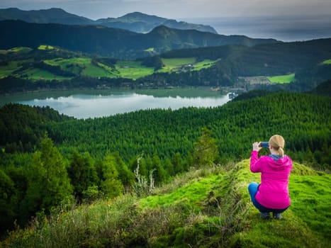Female traveller taking picture of the crater Furnas Lake, Sao Miguel island, Azores, Portugal