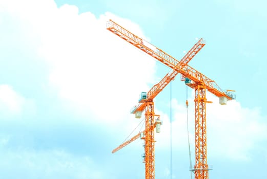 Two orange crane in cross on blue sky