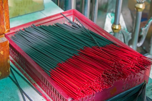 Many black incense sticks in a red basket.