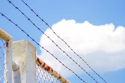 Barbed wire fence and white grating fence With blue sky
