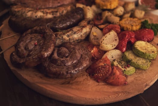 Grilled different meat and fish sausages with vegetables and spices on wooden background