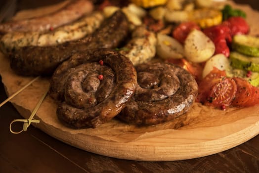 Grilled different meat and fish sausages with vegetables and spices on wooden background
