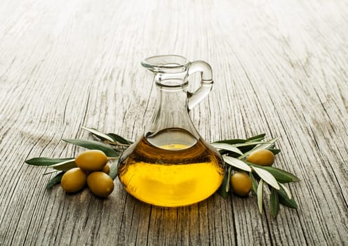Olive oil and olive branch on wooden table