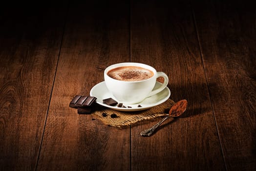 Cup of hot chocolate and cappuccino on wooden background.