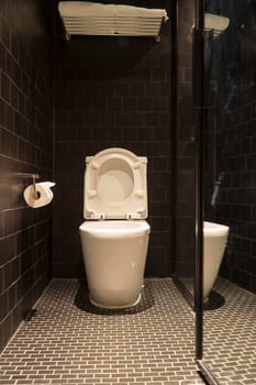 Black bathroom have white toilet and white towel