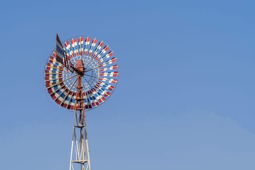 Wind turbine of red, white, blue color and old with blue sky.
