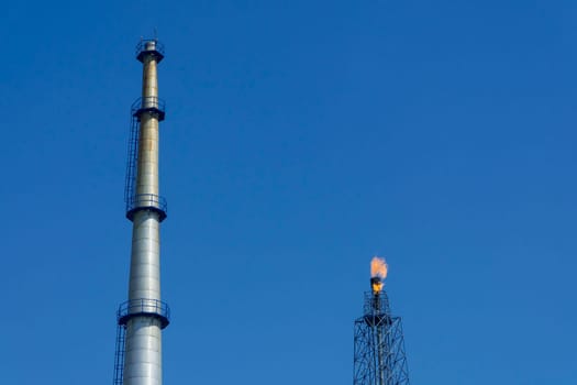 Gas flares in petroleum refinery  with blue sky background