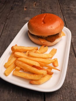 Fish burger with French fries on a white plate
