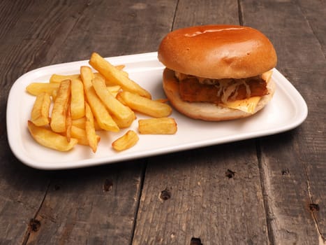 Fish burger with French fries on a white plate