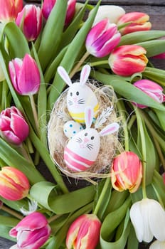 Small Easter nest with colorful eggs and tulips