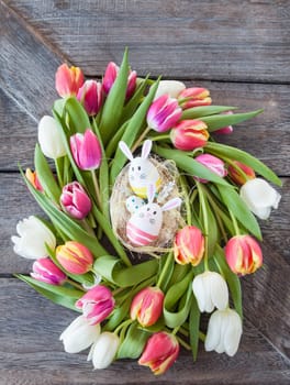 Small Easter nest with colorful eggs and tulips