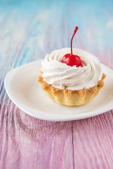 Tasty mini cake with cherry on a color gradient background