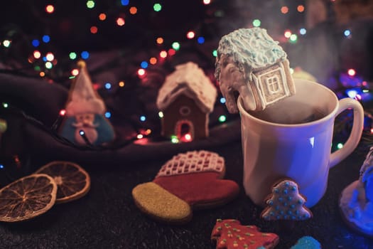 Christmas cookies and cup of tea on dark color bokeh lights background
