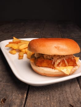Fish burger with French fries on a white plate