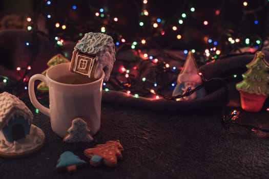 Christmas cookies and cup of tea on dark color bokeh lights background