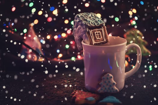 Christmas cookies and cup of tea on dark color bokeh lights background