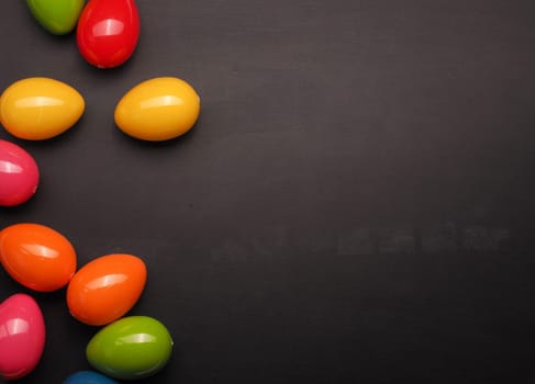 Colorful plastic Easter eggs on a chalkboard with space for text or image