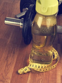 cold water and measuring tape with dumbbells on a wooden floor
