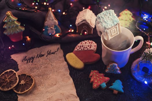 Christmas cookies and cup of tea on dark color bokeh lights background