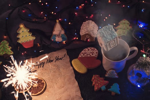 Christmas cookies and cup of tea on dark color bokeh lights background