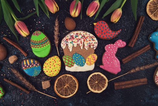 Tulips and gingerbread cookies on darken concrete background for Easter.