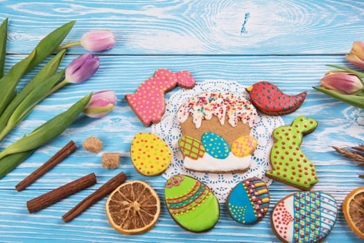 Tulips and gingerbread cookies on white and blue wooden background for Easter.