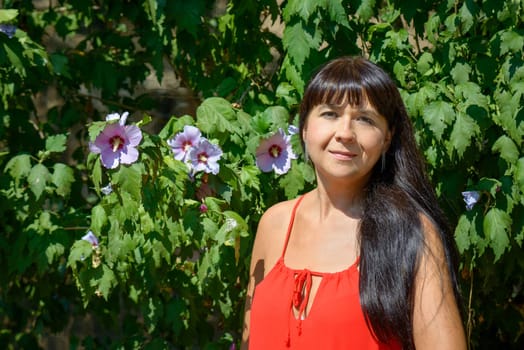 girl smiling and posing in background green plant and flower of ibiscus