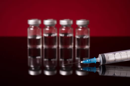 medical vials and syringe isolated on red black background