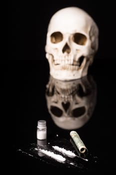 cocaine or other illegal drugs that are sniffed by means of a tube and Skull, isolated on black glossy background