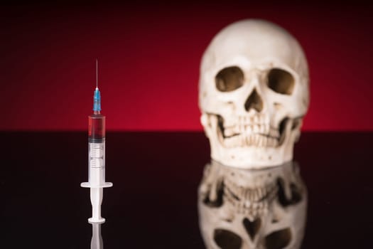 Blurry Skull and syringe, isolated on black red background with glossy reflection
