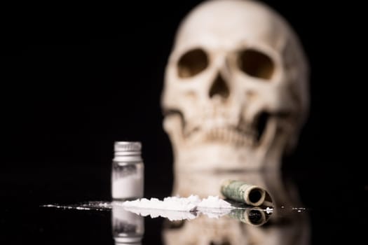 cocaine or other illegal drugs that are sniffed by means of a tube and Skull, isolated on black glossy background