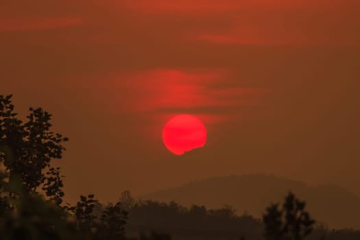 Sun shining through the clouds with silhouetted mountians