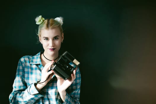 studio portrait of a girl with retro camera. young beautiful woman hipster, holding a camera, being in the room