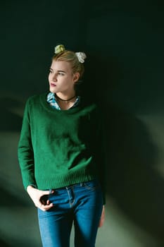 studio portrait of a girl. hipster young beautiful woman in a green sweater and blue jeans, while in the room