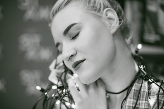 Portrait of a young woman with lights. beautiful girl with white hair dyed, holding christmas lights