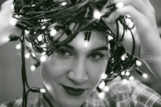 portrait of a beautiful young woman who wears on his head the Christmas lights, instead of a hat