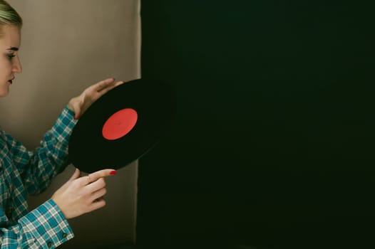 a woman with the disc. young beautiful hipster girl with old vintage vinyl record in his hands. she wants to listen to music on old player