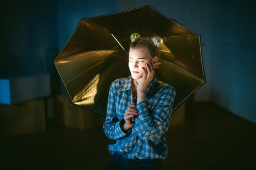 studio portrait of a young woman with golden umbrella